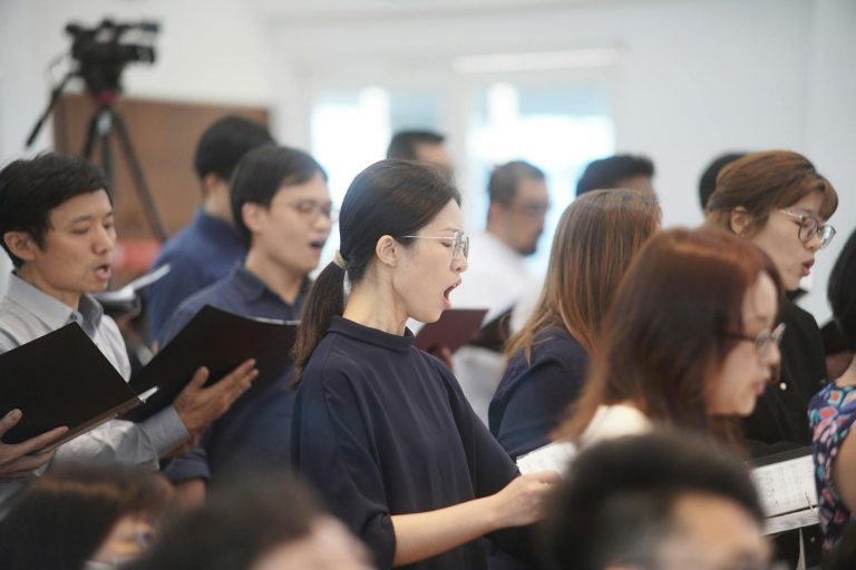A choir group rehearsing indoors, focusing on singing and teamwork.