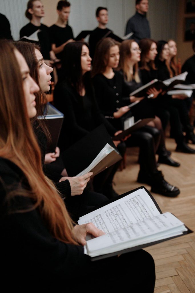 A choir performing indoors with music sheets, showcasing harmony and teamwork.