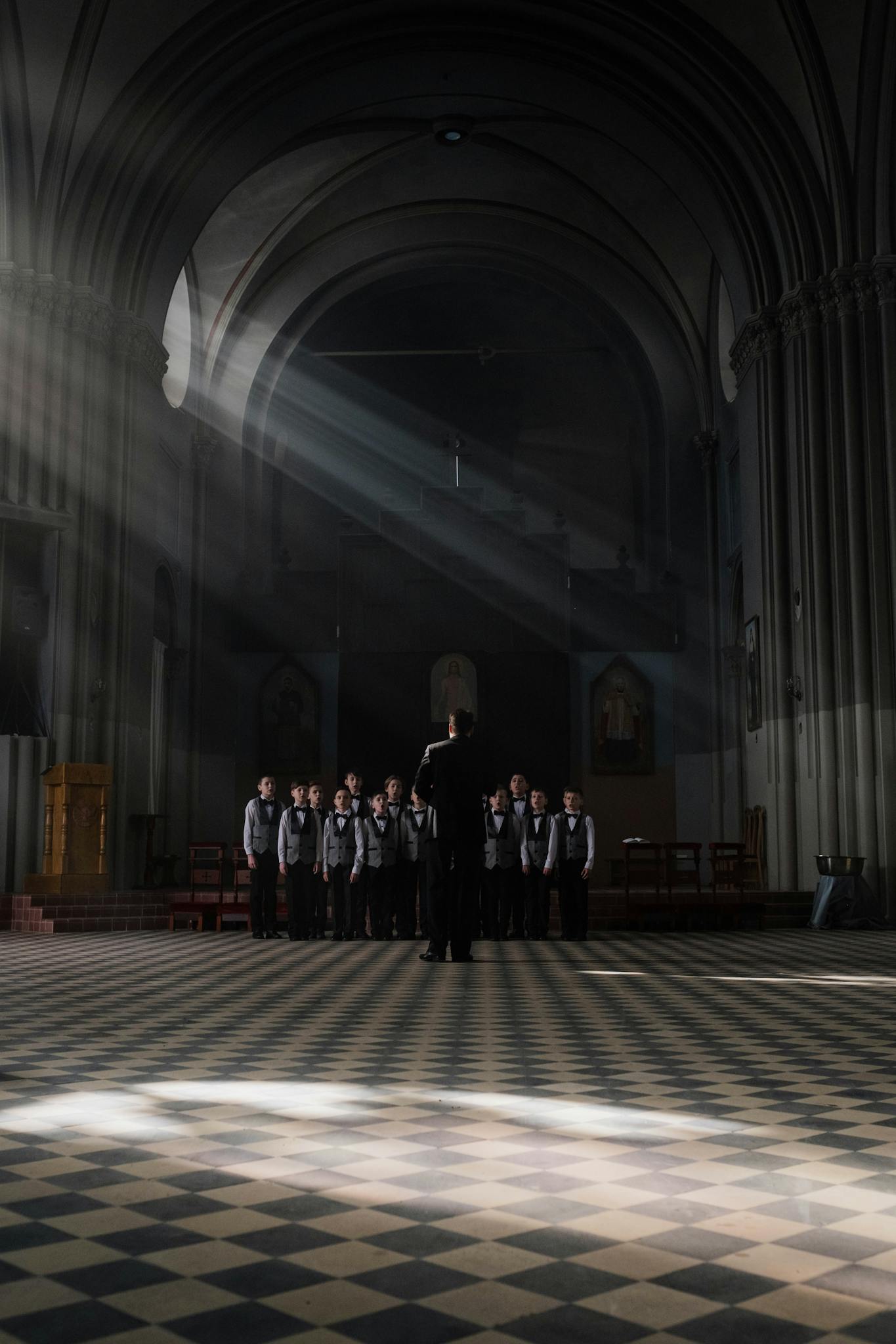 A group of boys practicing choir in a grand, dimly lit cathedral.