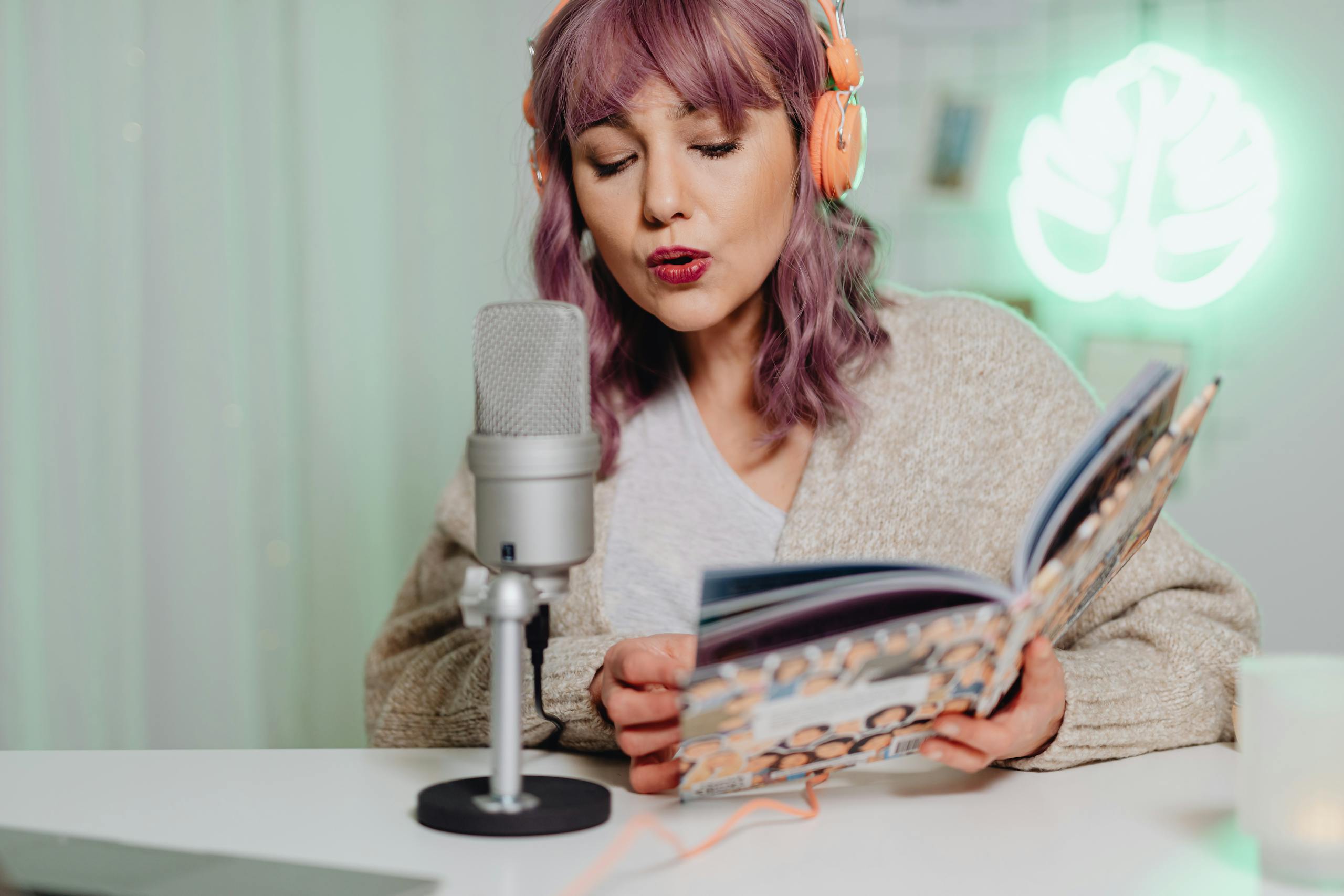 podcasting while reading a book, wearing orange headphones.