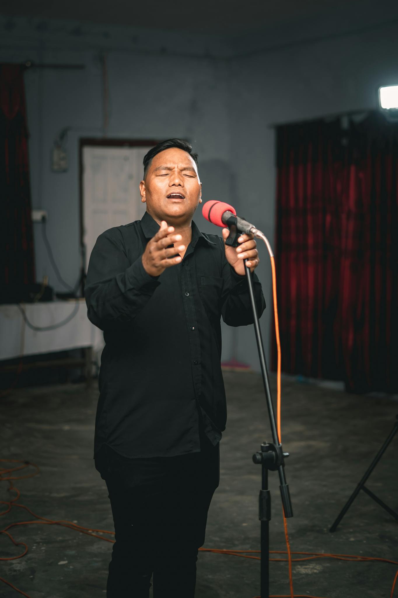 Male singer passionately performing indoors with a microphone and subtle lighting.