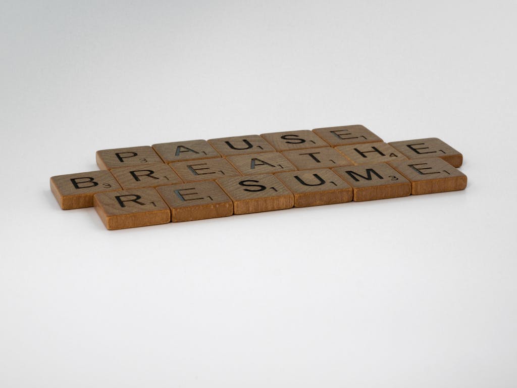 Scrabble tiles spelling 'Pause, Breathe, Resume' on a white background, symbolizing mindfulness and relaxation.