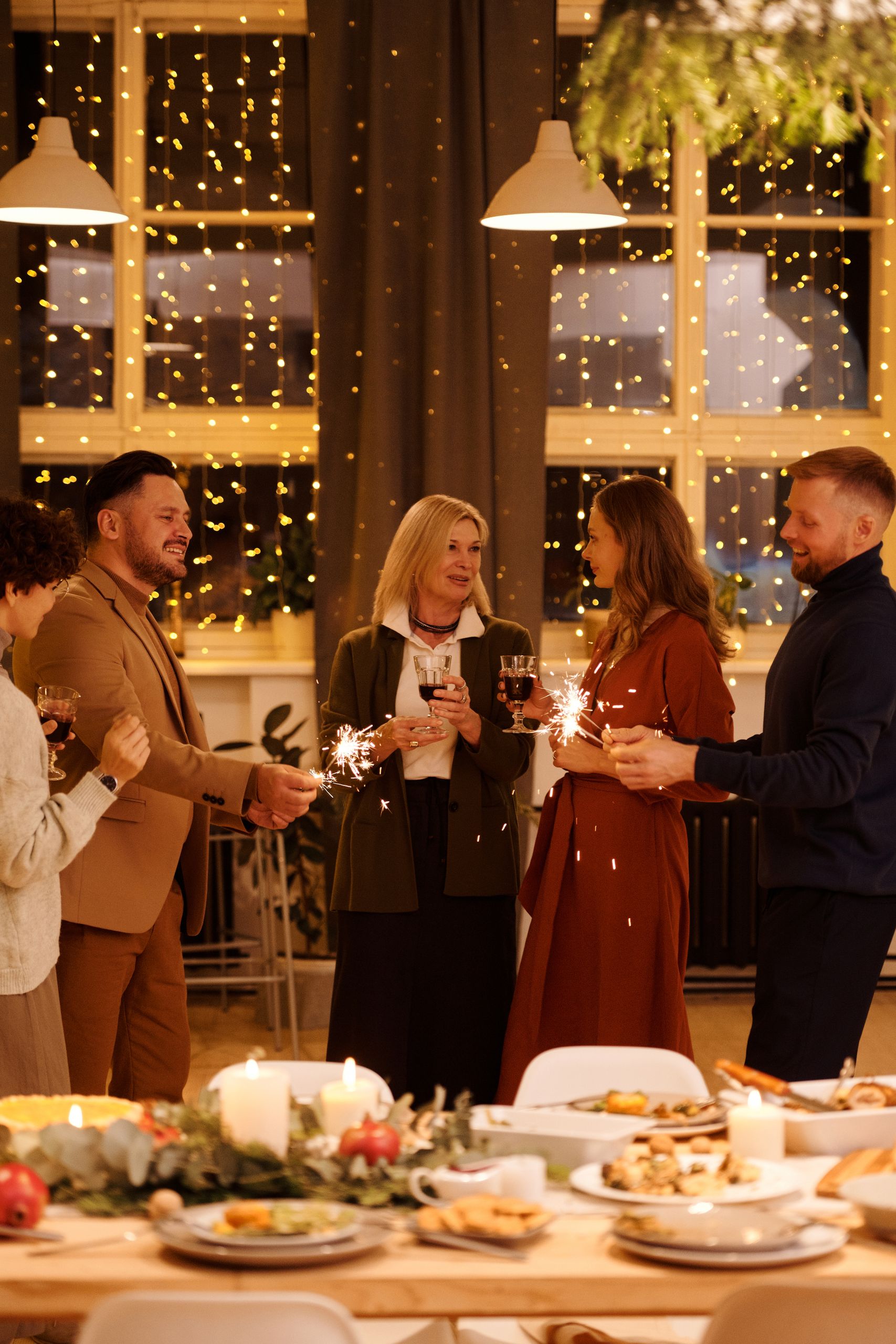 A joyful family gathering celebrating with sparklers and festive food indoors.